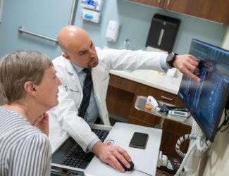 Dr. Asfahani, Parker spine neurosurgeon, goes over imaging results with a lumbar fusion patient.