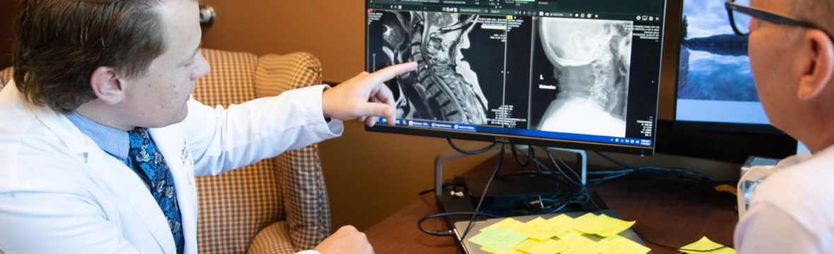 Dr. Zain Allison, a Denver spine surgeon, discusses types of neck pain and treatments with a patient.