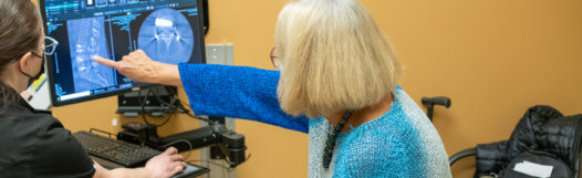 Image of a patient looking at images that show her adult onset scoliosis, and speaking about treatment with her provider.