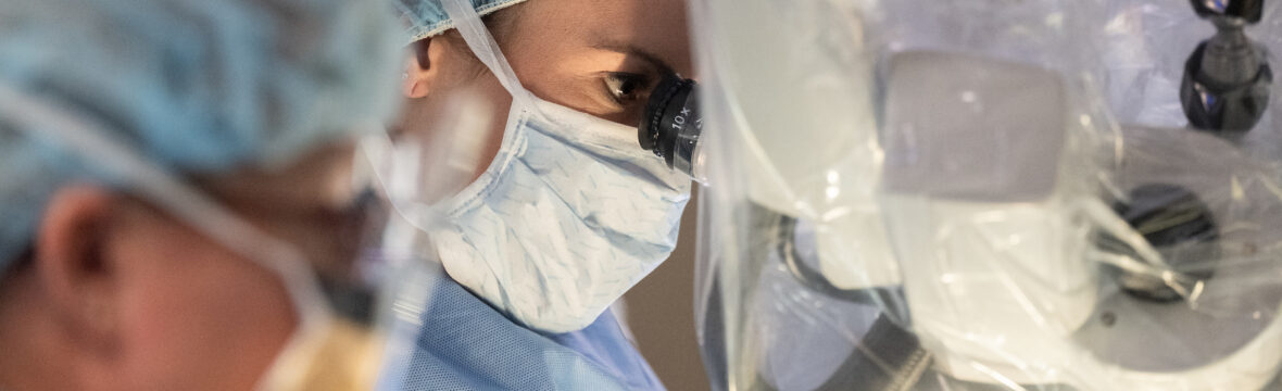Denver spine surgeon looking through microscope during back surgery.