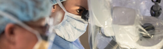 Denver spine surgeon looking through microscope during back surgery.