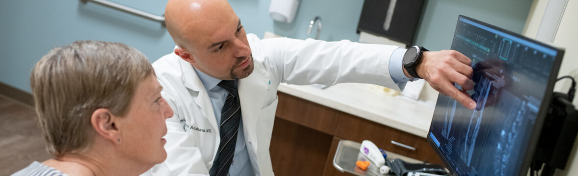 Fusion Provider Blog Image Dr. Asfahani looks at spine imaging with patient to discuss fusion.