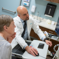 Dr. Asfahani looks at spine imaging with patient to discuss fusion.